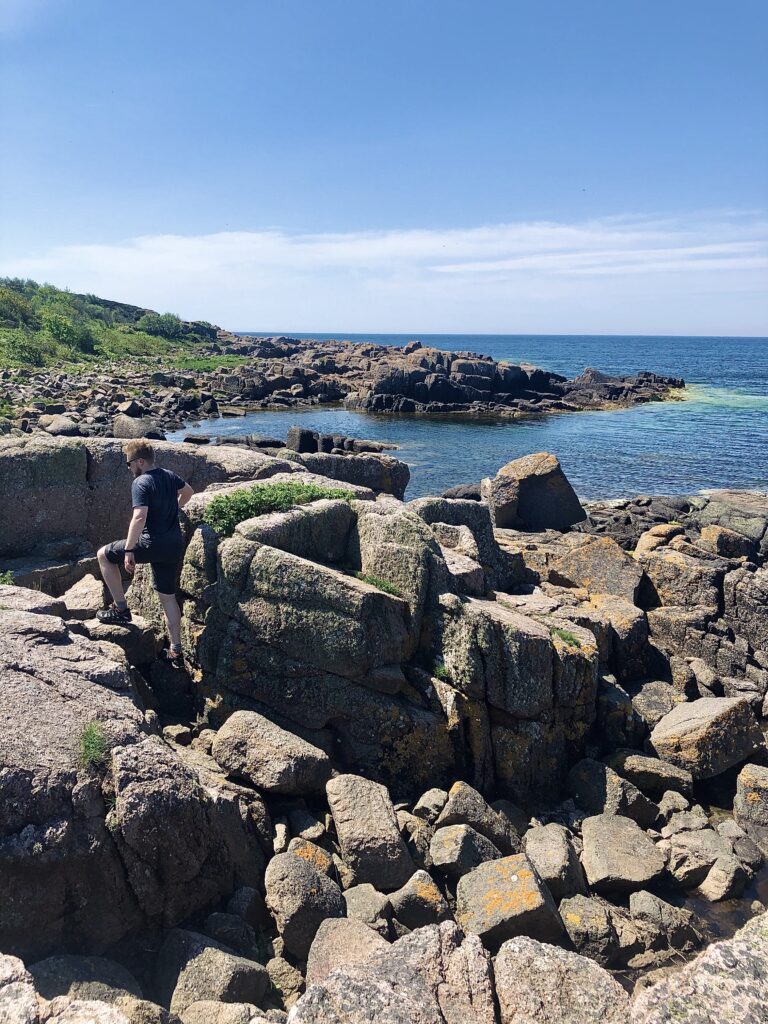 Daniel går på klipperne ud fra Hammerodde Fyr